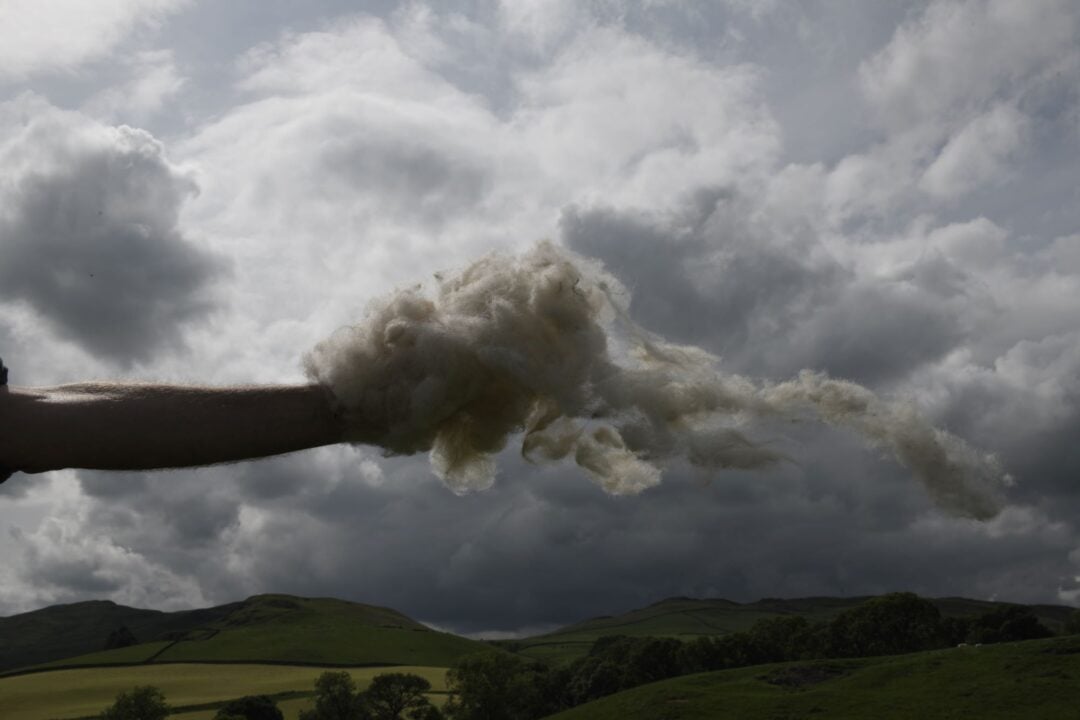 Image of hand holding a cloud in the sky.