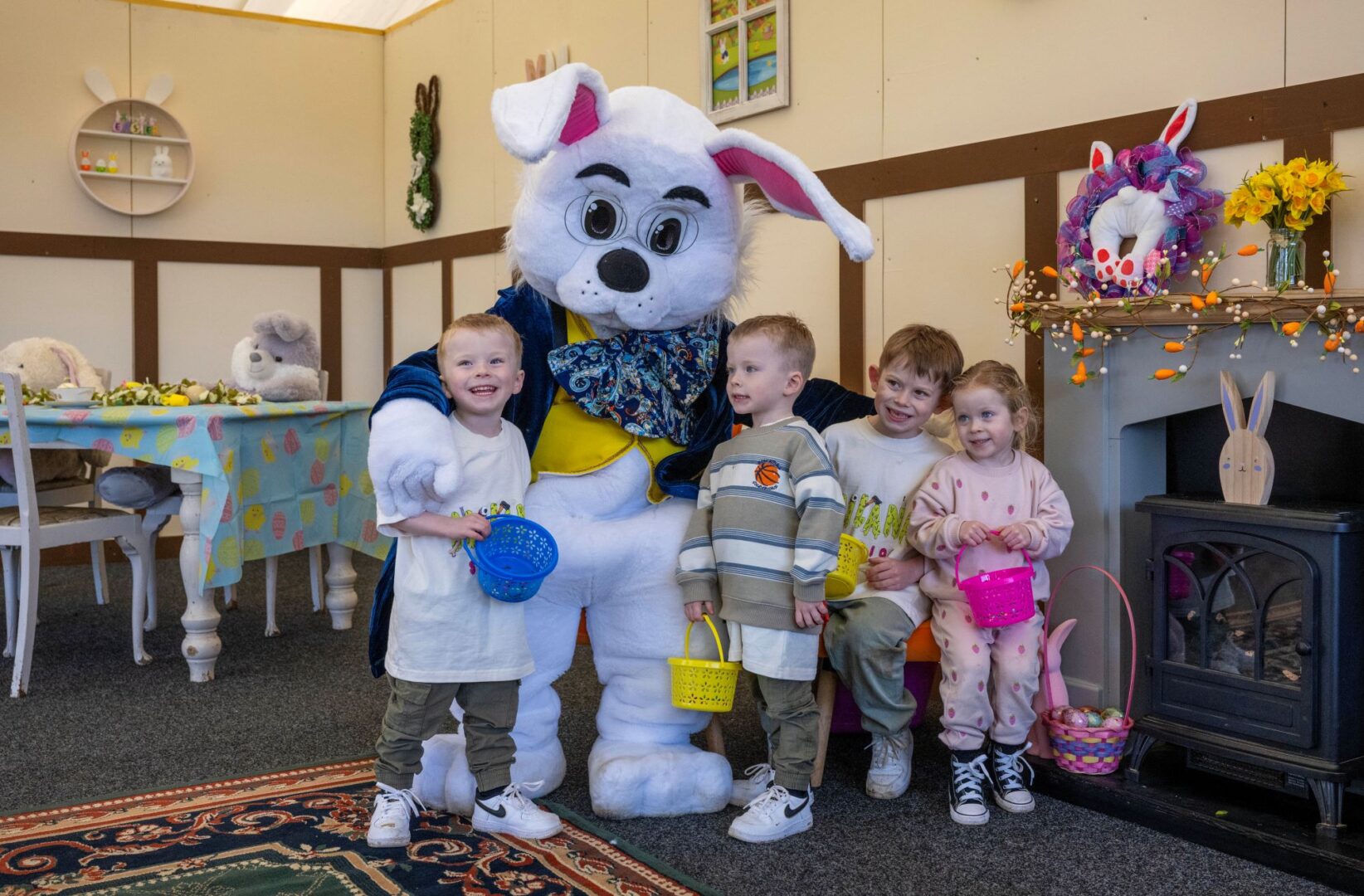 Person dressed in cartoon rabbit costume, surrounded by group of young children.