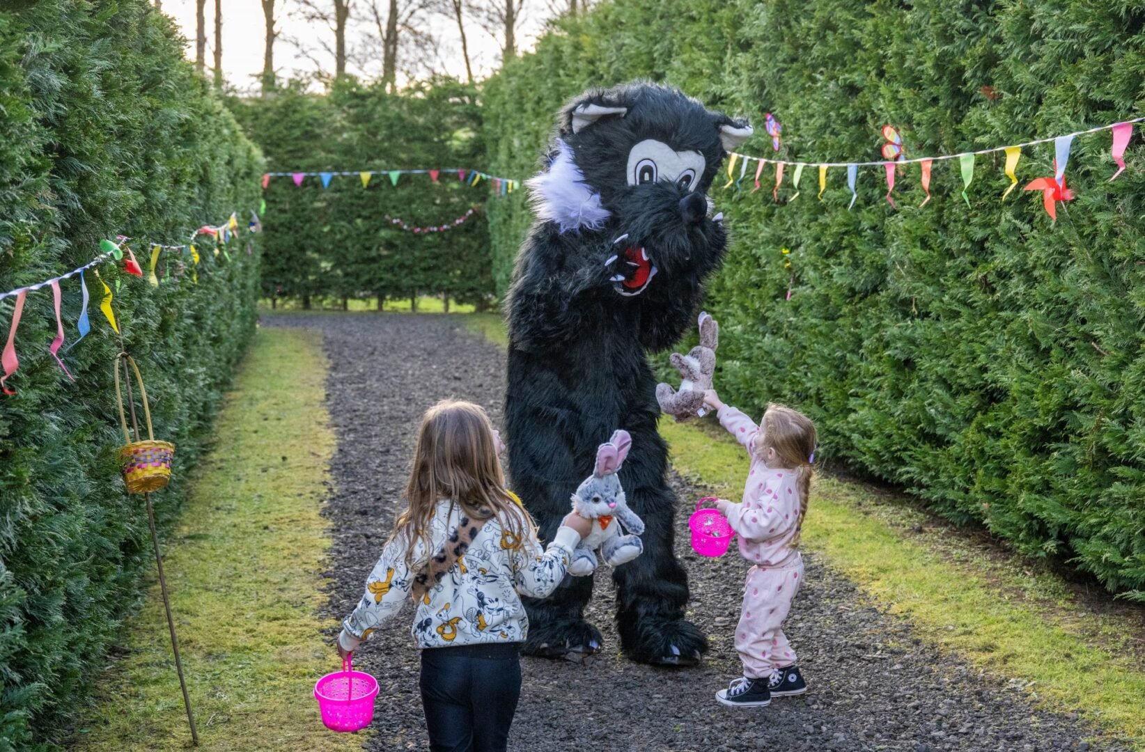 Person dressed in cartoon wolf costume, with 2 young children.