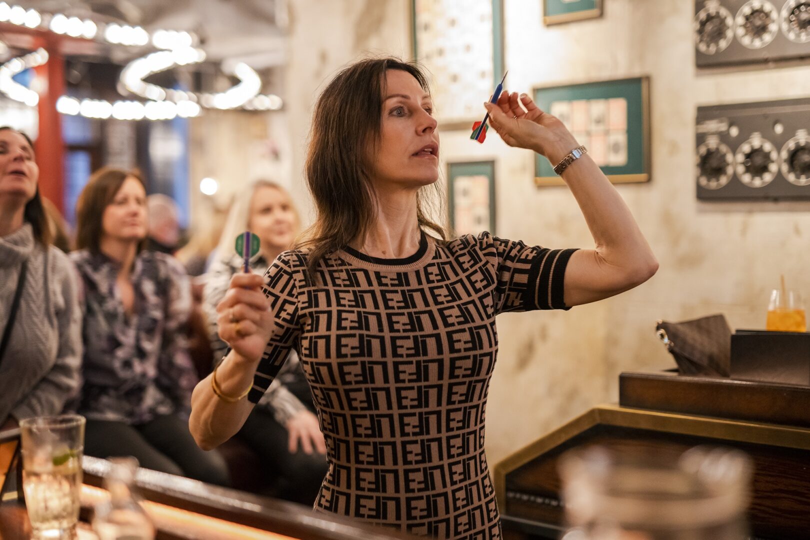 Lady with dart in hand aiming at board at Flight Club.