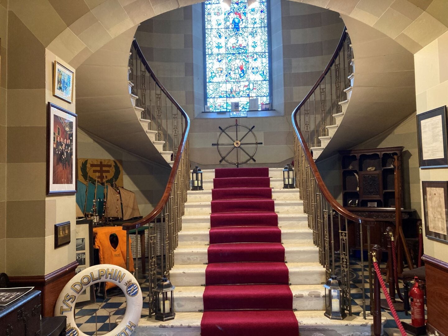 Staircase leading to landing to stained glass window.
