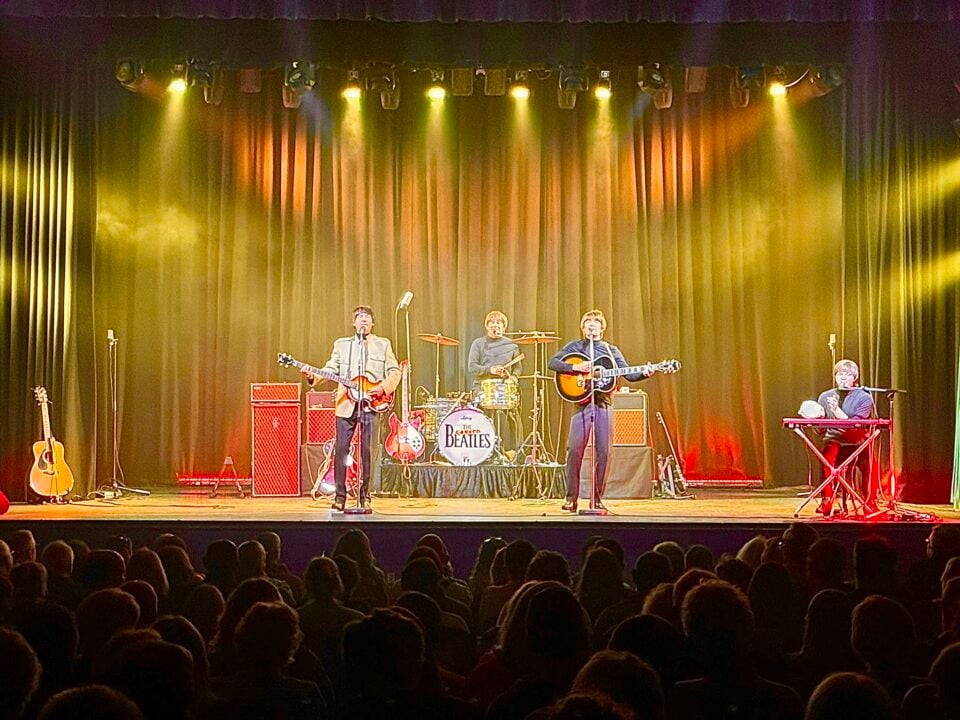 4-person band on stage - 2 on guitars, one on drums and one on keyboard.
