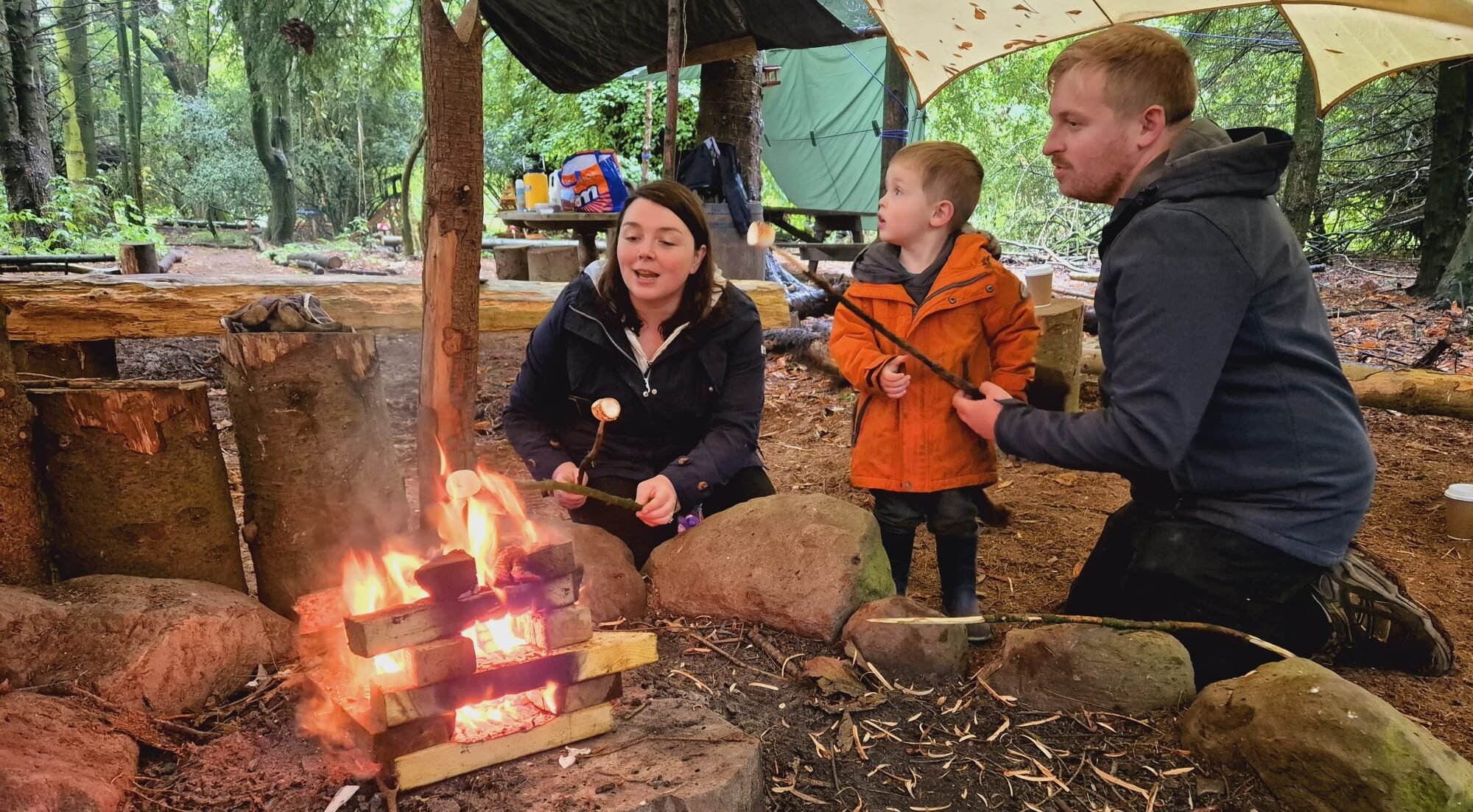 Child with parents next to outdoor fire
