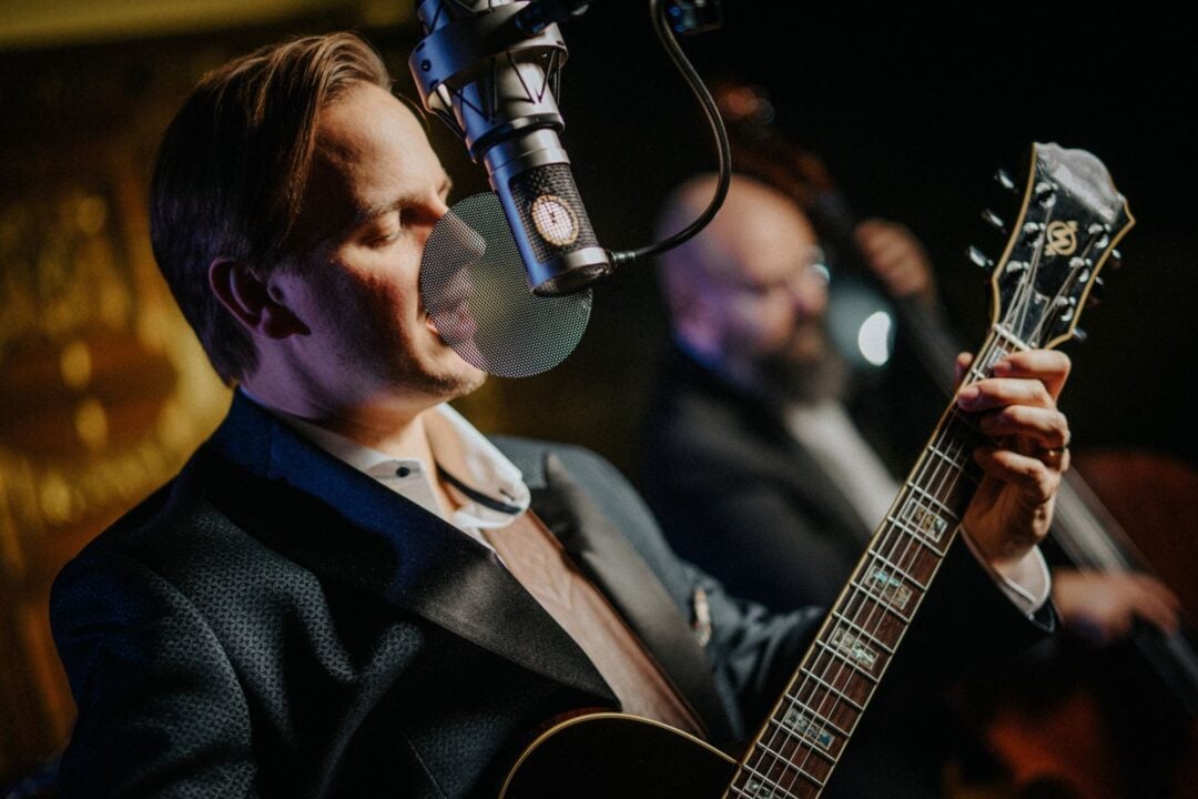 Man playing a guitar and singing into a microphone.