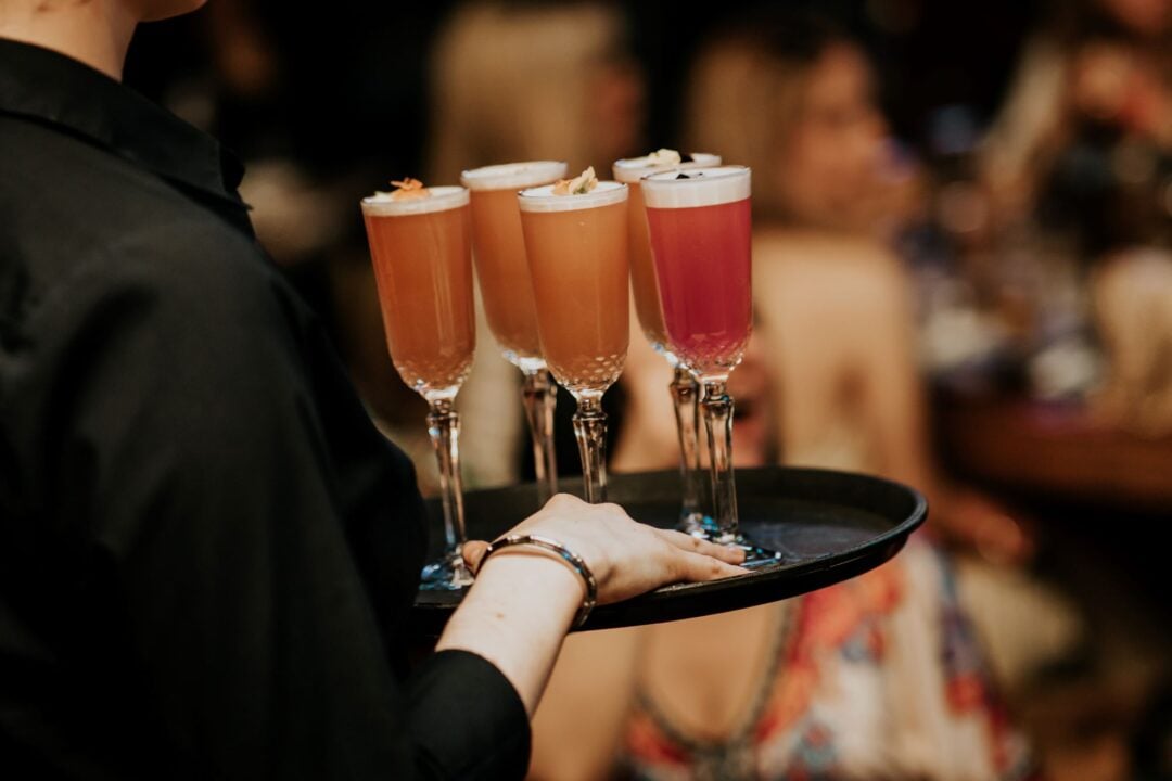 Person carrying a tray of drinks on a tray.