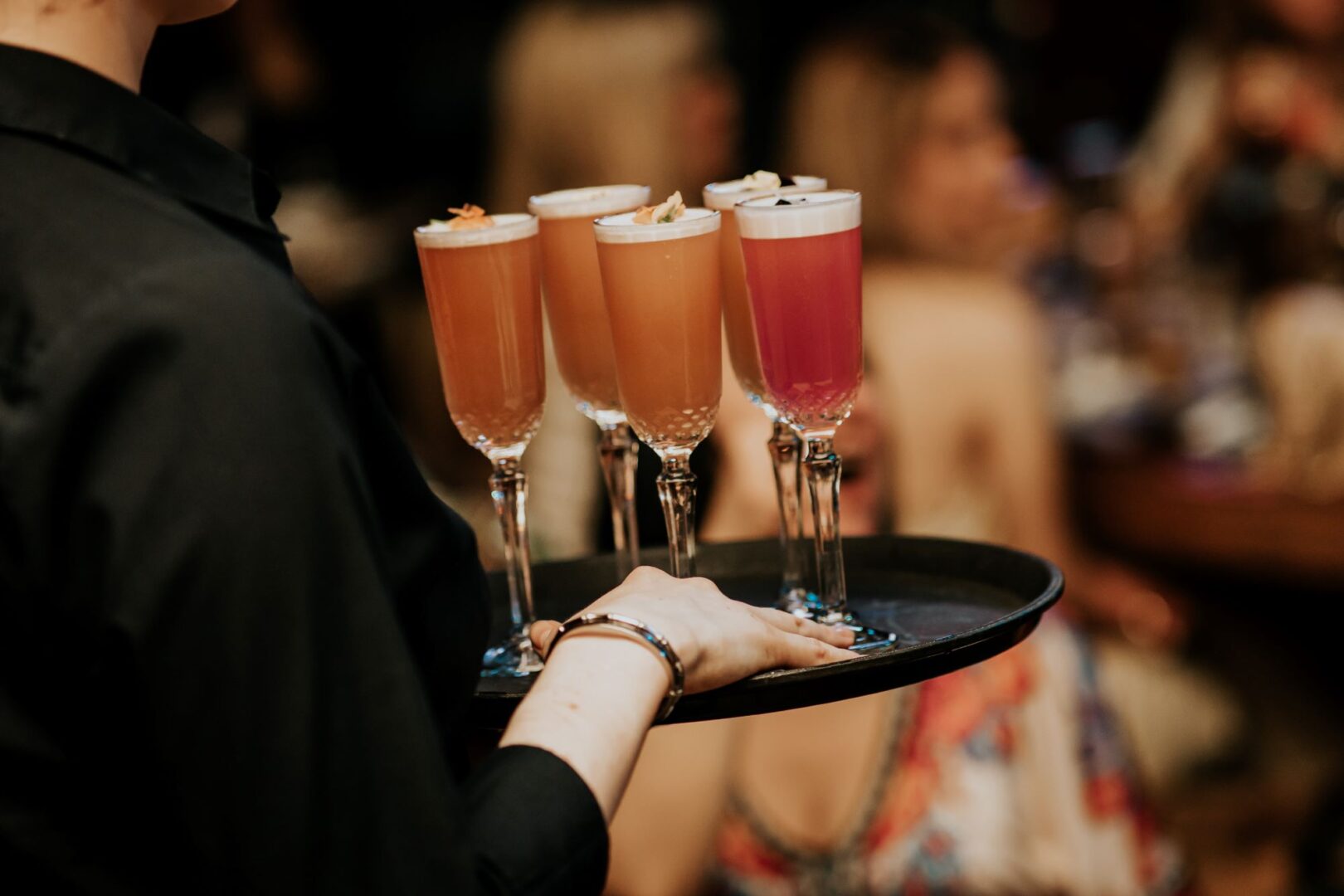 Person carrying a tray of drinks on a tray.