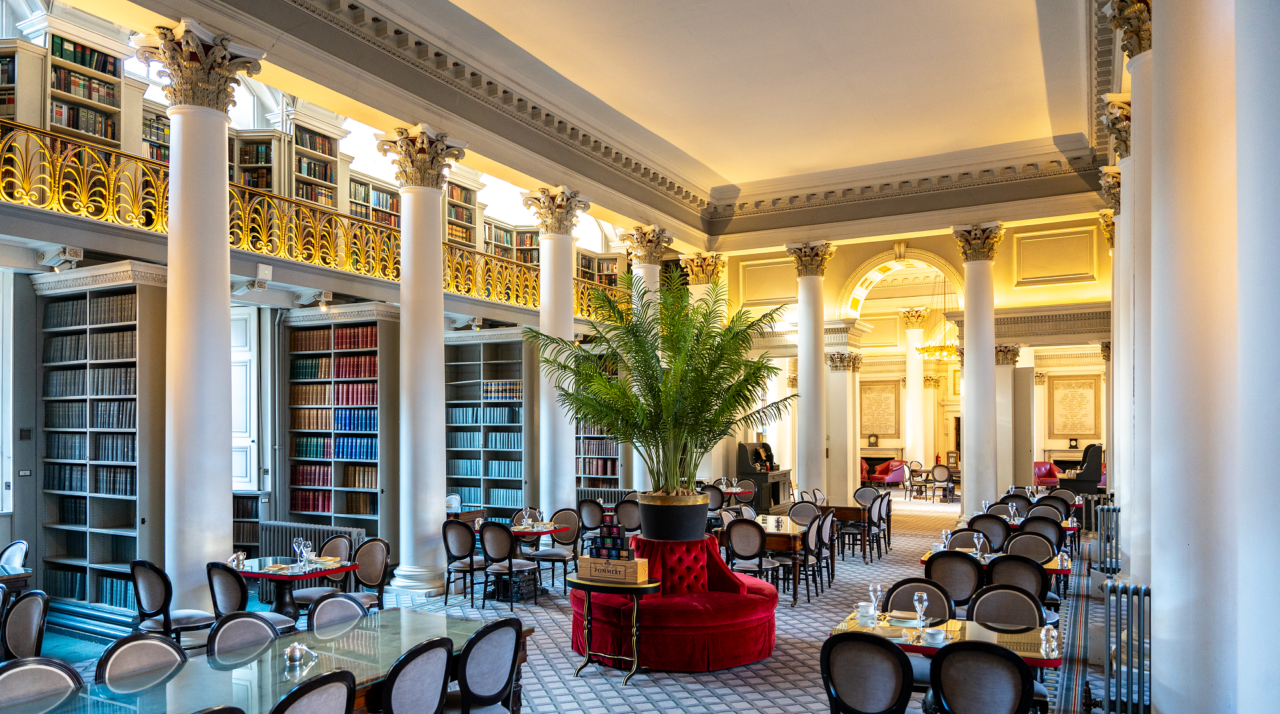 Luxurious room with white columns filled with dining tables and chairs.