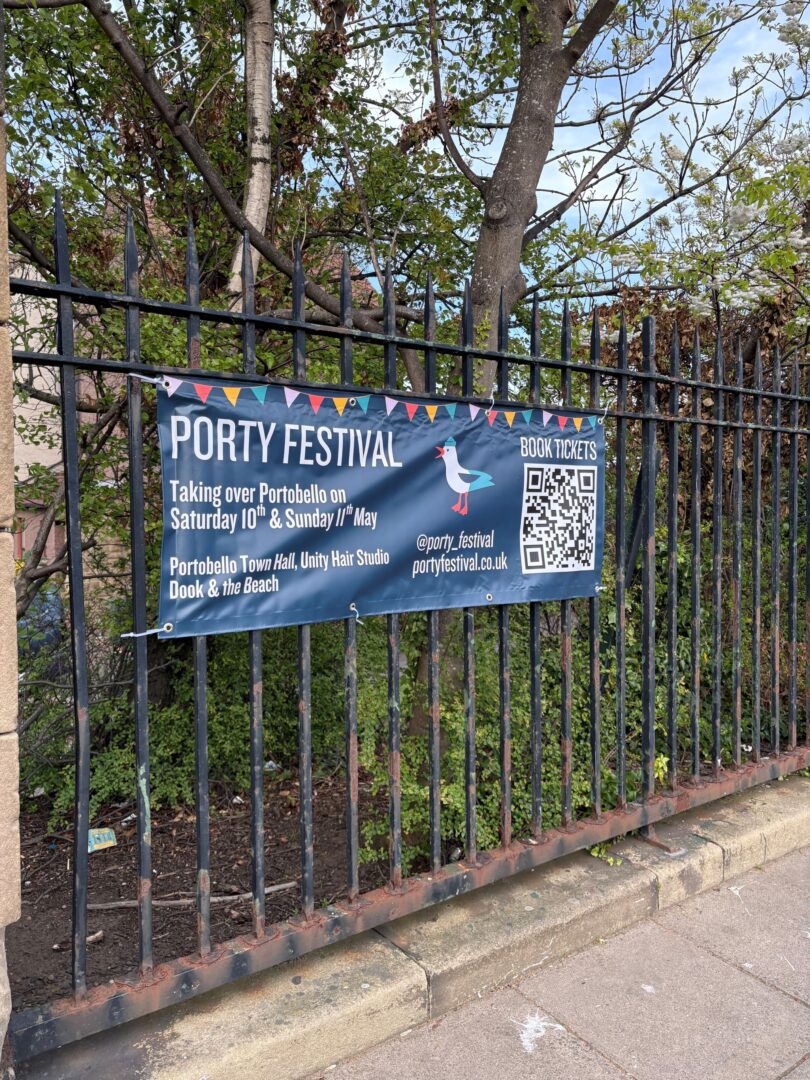Poster advertising Porty Festival hung on a metal fence.