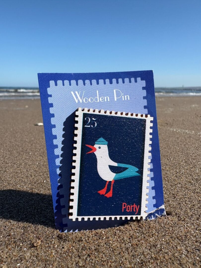 Enlarged postage stamp with a seagull on it, sitting on a sandy beach.