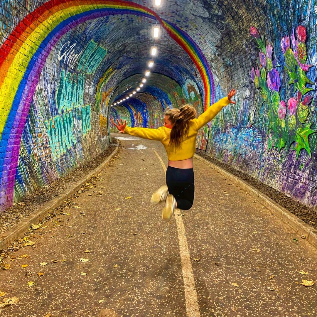 Girl with yellow top jumping in Colinton Tunnel