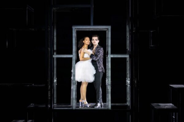 A man and a woman stand in the middle of a dark stage during a scene from the Three Penny Opera ,© Jess Shurte