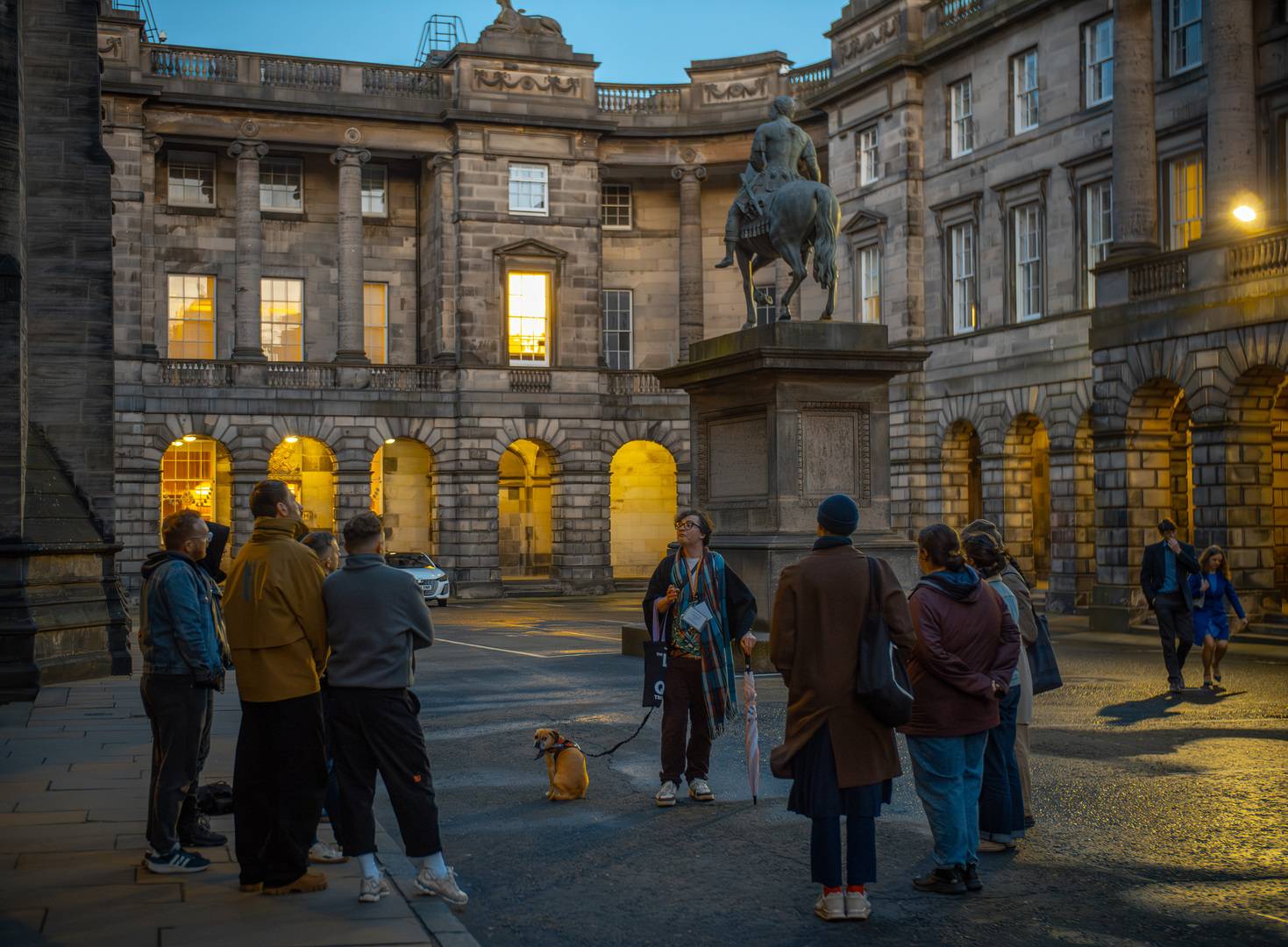 The tour guide talking to his group in front of a state of a man on a horse
