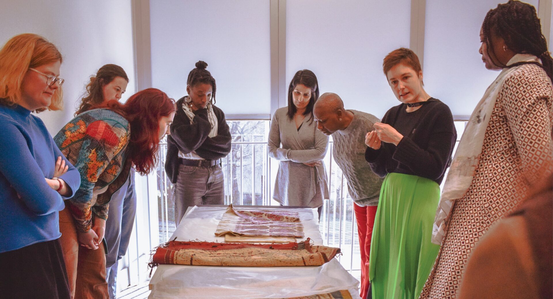 A group of women standing round a table looking at various printed fabrics