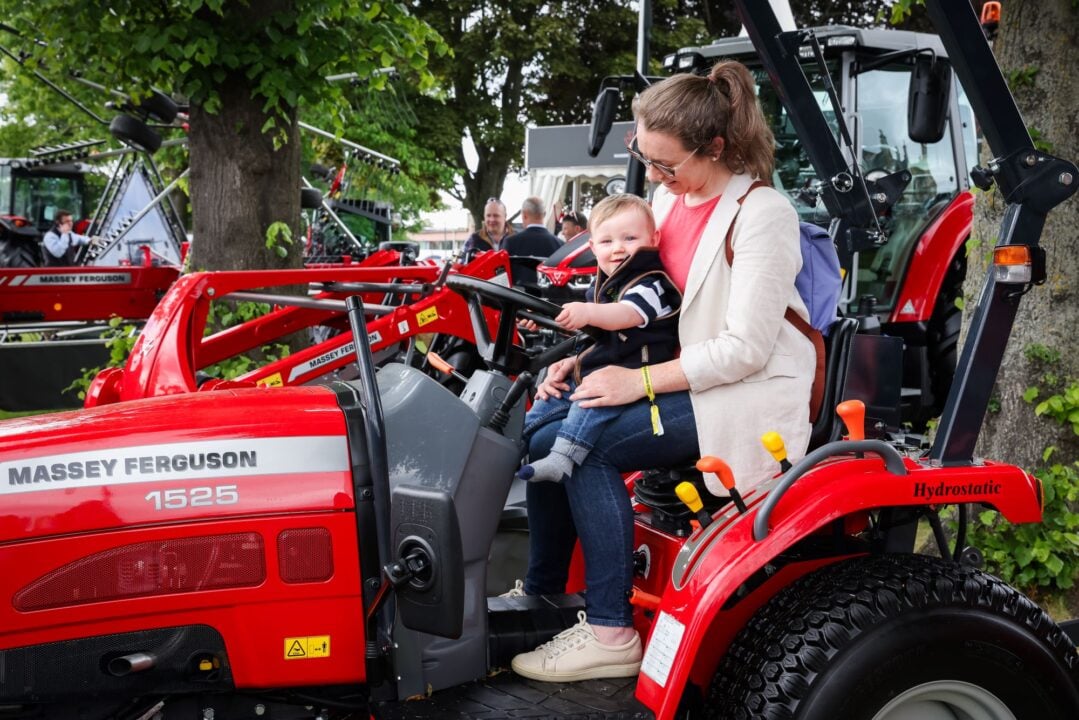 Women and toddler sitting on a red tractor.