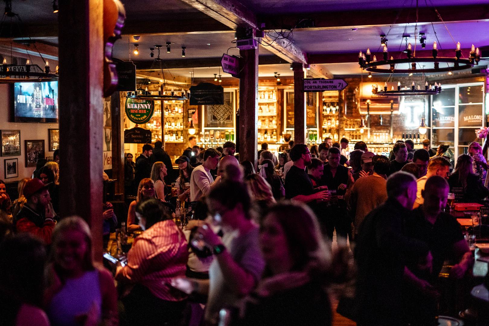 Large crowd inside a pub with exposed wooden beams and chandeliers ,© Malones Edinburgh