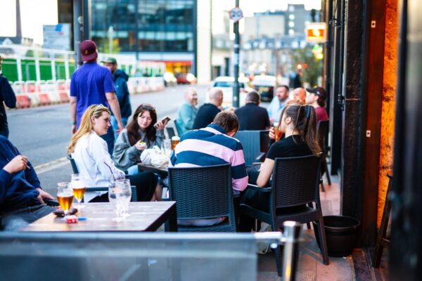 Customers sit at tables on the street outside a pub,© Malones Edinburgh