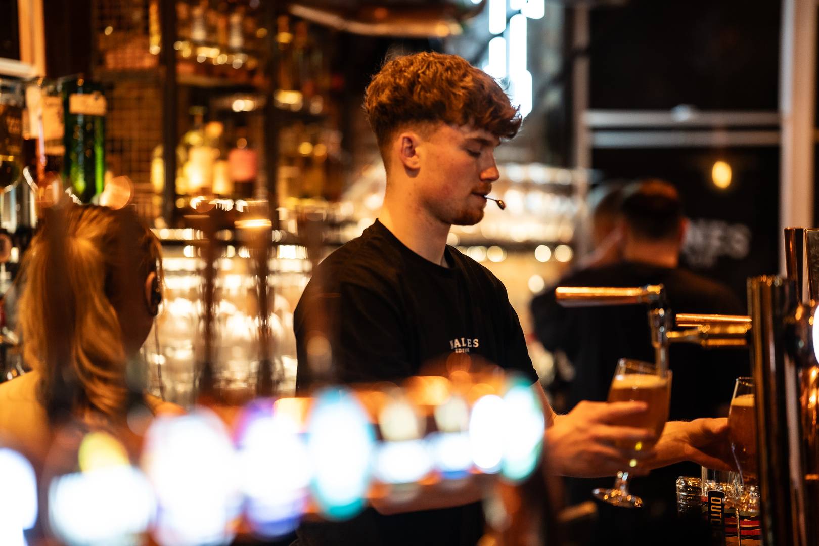 Bar man pours pints of Tennent's behind the bar,© Malones Edinburgh