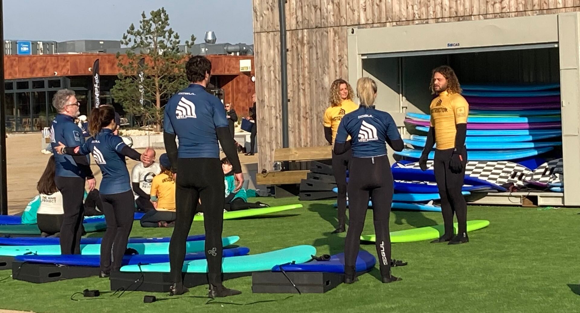 Lost Shore surf instructors showing group of learners how to surf on land on special surf boards that mimic a wave without being on the water