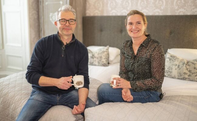 A couple sitting on a bed at Kingsway Guest House