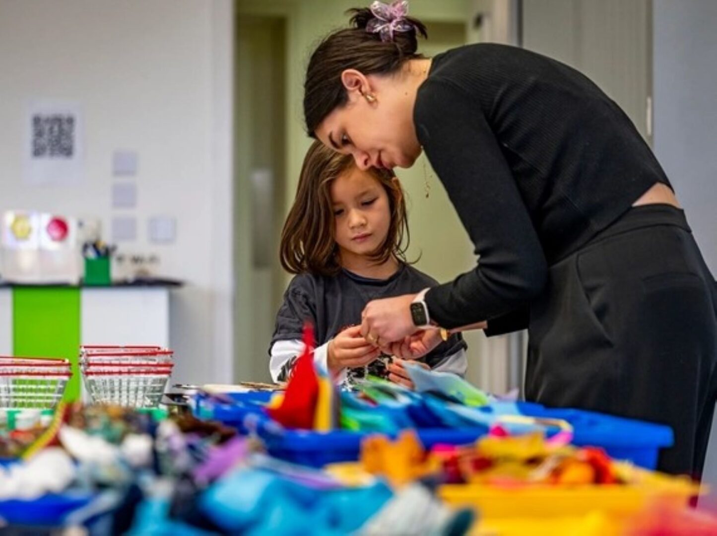 A woman helping a younger girl with fabric