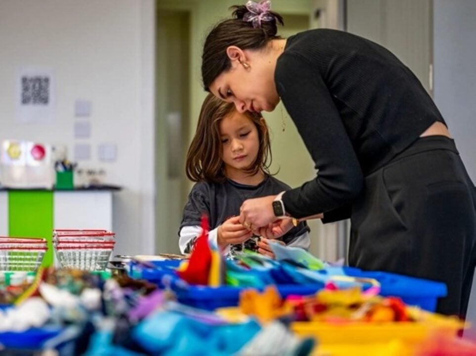 A woman helping a younger girl with fabric