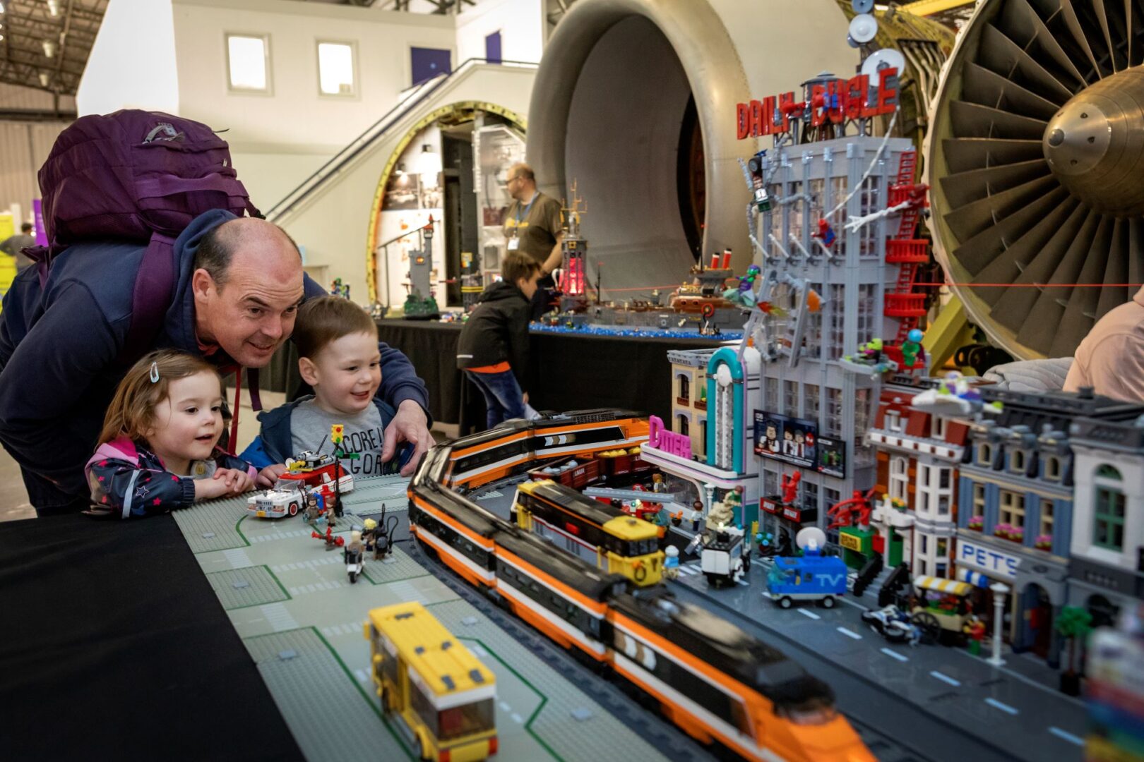 A man and two children looking at a LEGO city
