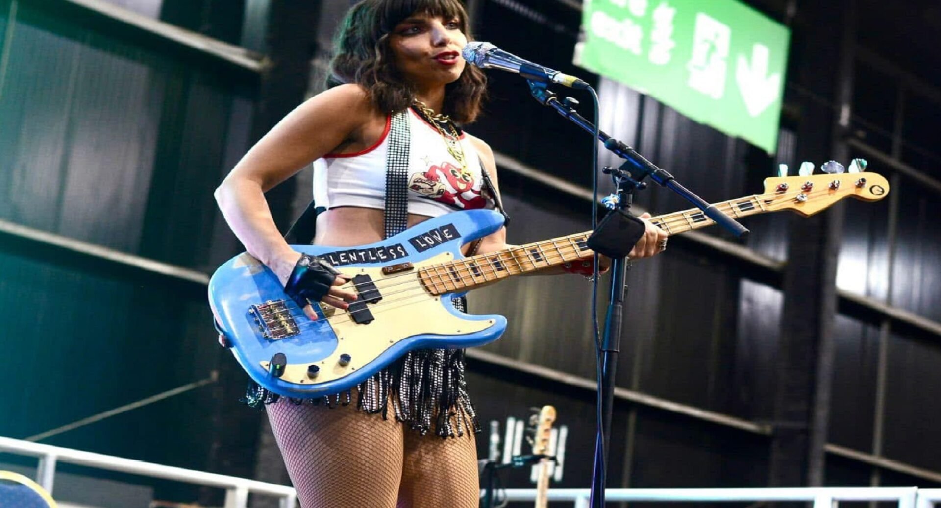 A woman singing into a microphone with a guitar
