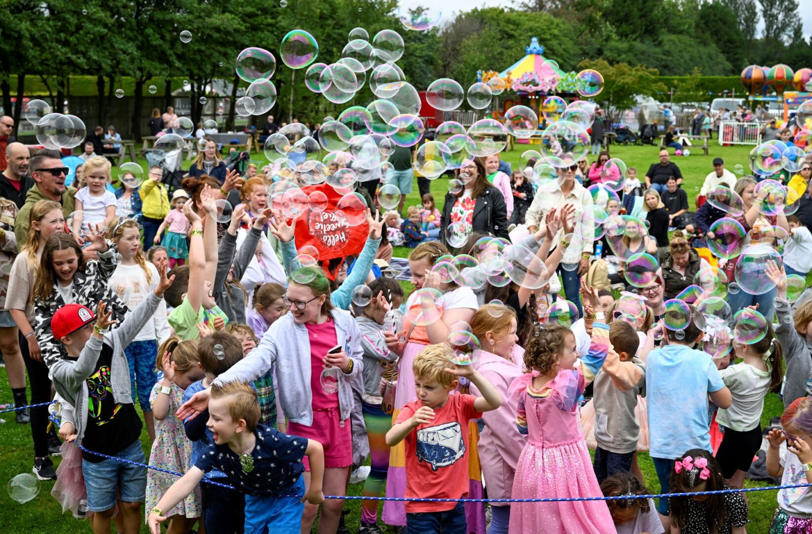Crowd of people in the outdoors, playing with large bubbles.