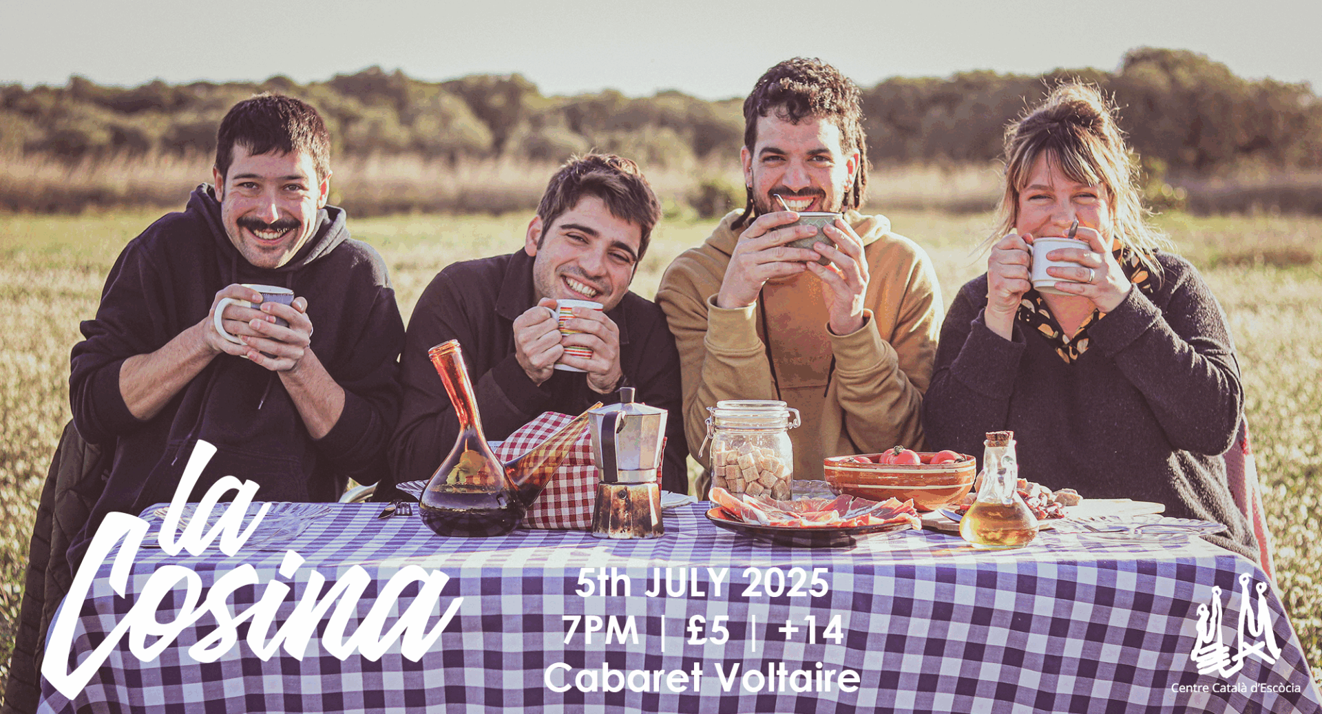4 people sitting round a table in the outdoors. The table is full of food and drink.