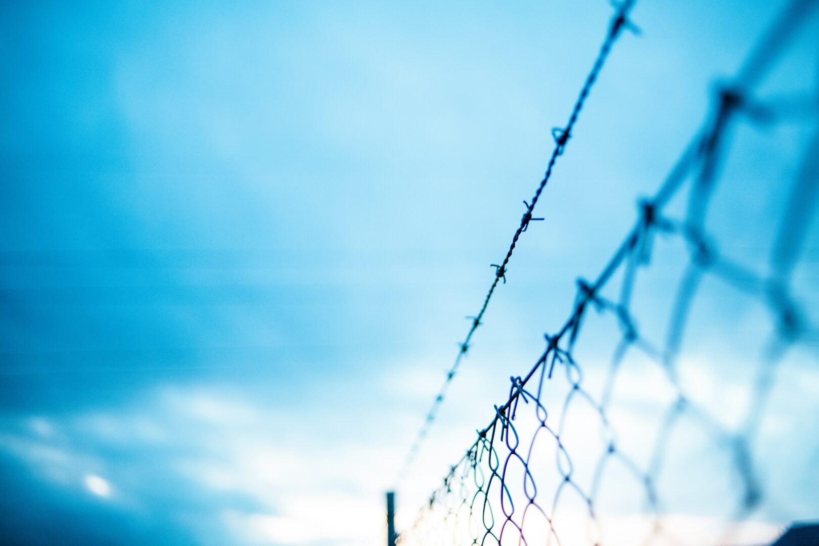 A barbed wire fence against a blue sky