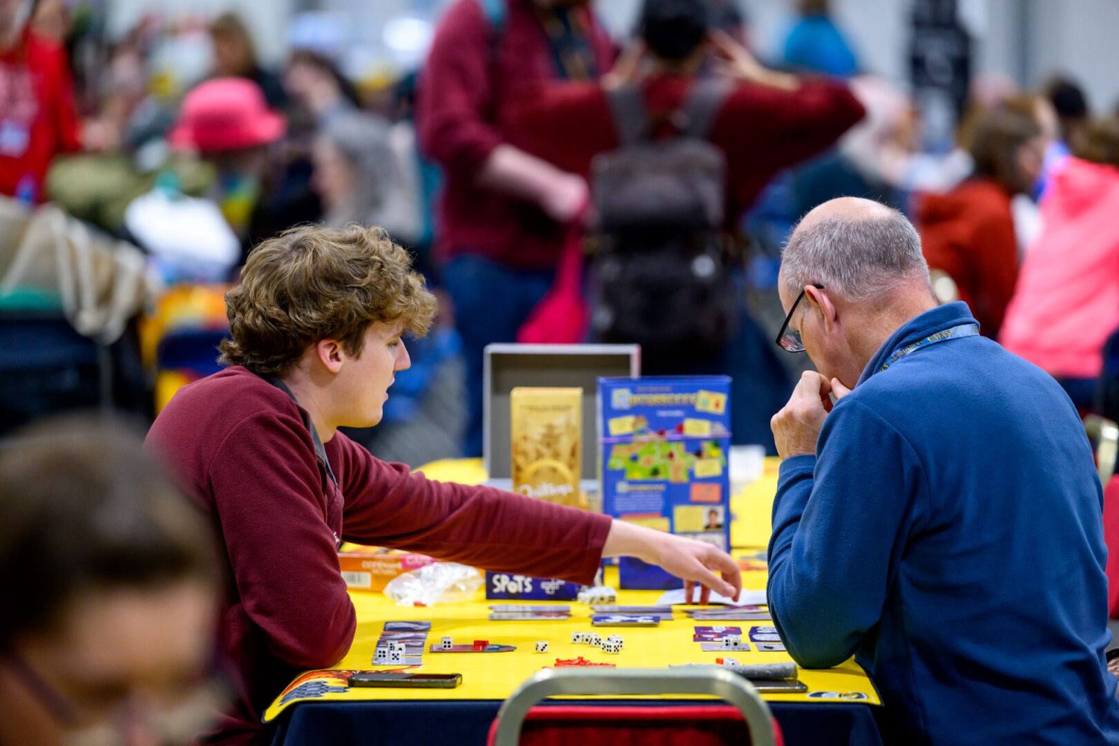 2 men sitting at a table playing a board game.