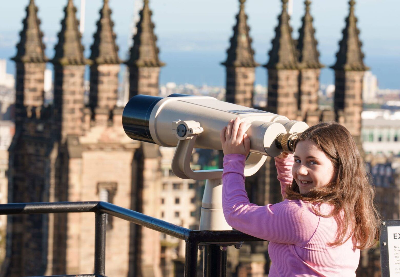 A young girl looks through a pair of binoculars over the skyline. Rooftop Terrace at Camera Obscura & World of Illusions, Edinburgh,© Camera Obscura & World of Illusions, Edinburgh