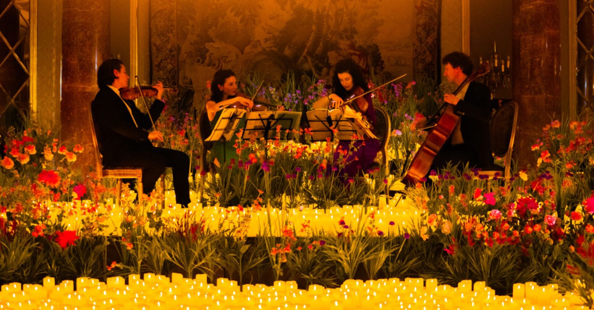 Close-up of musicians on a stage, surrounded by flowers and candles.