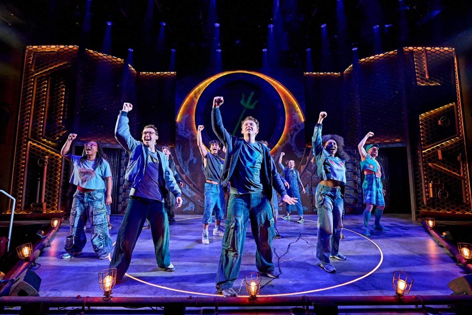 Group of people standing on a stage, all with their right arm in the air.