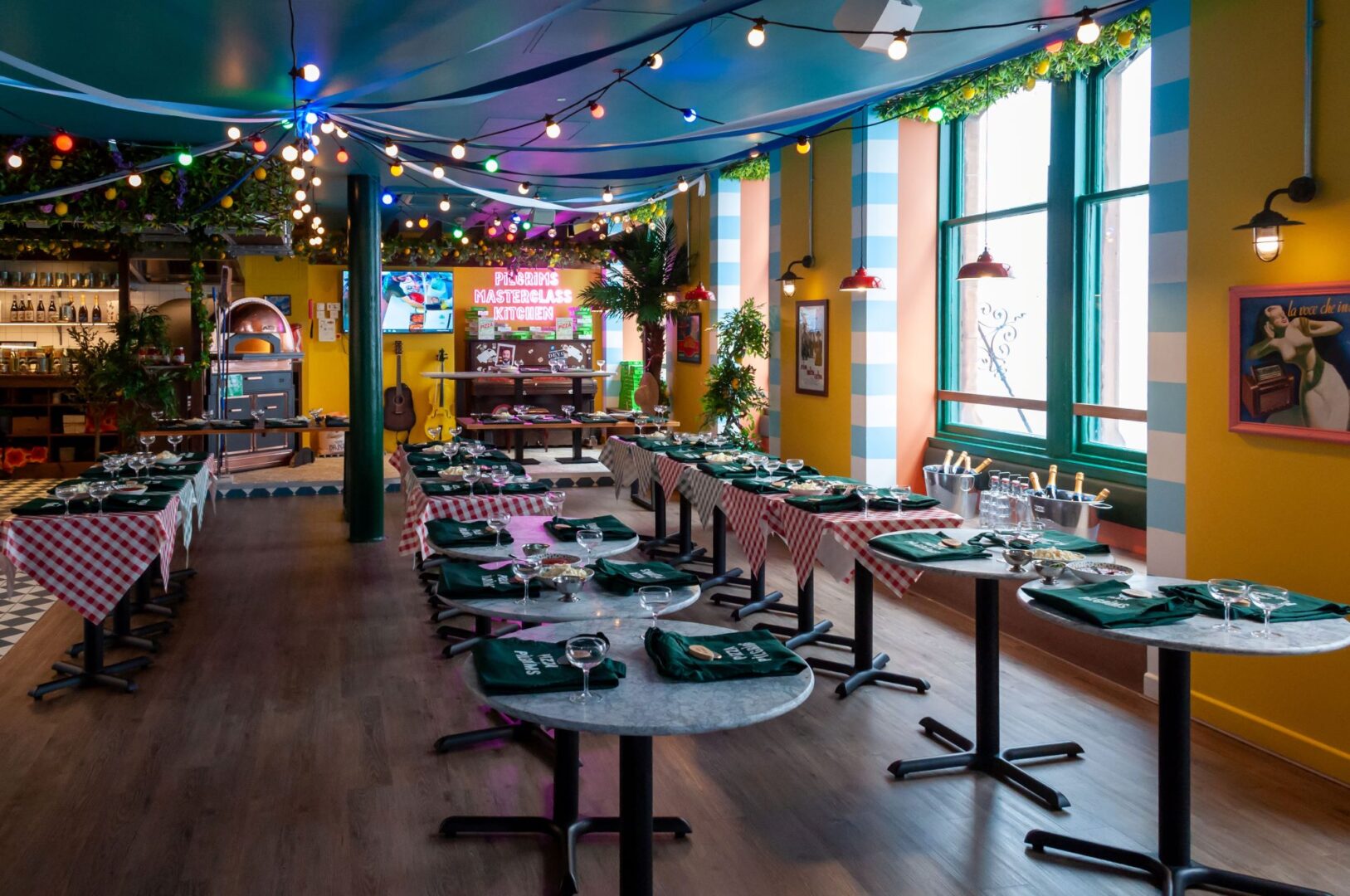 Inside of restaurant, with individual tables set up with aprons and glasses.