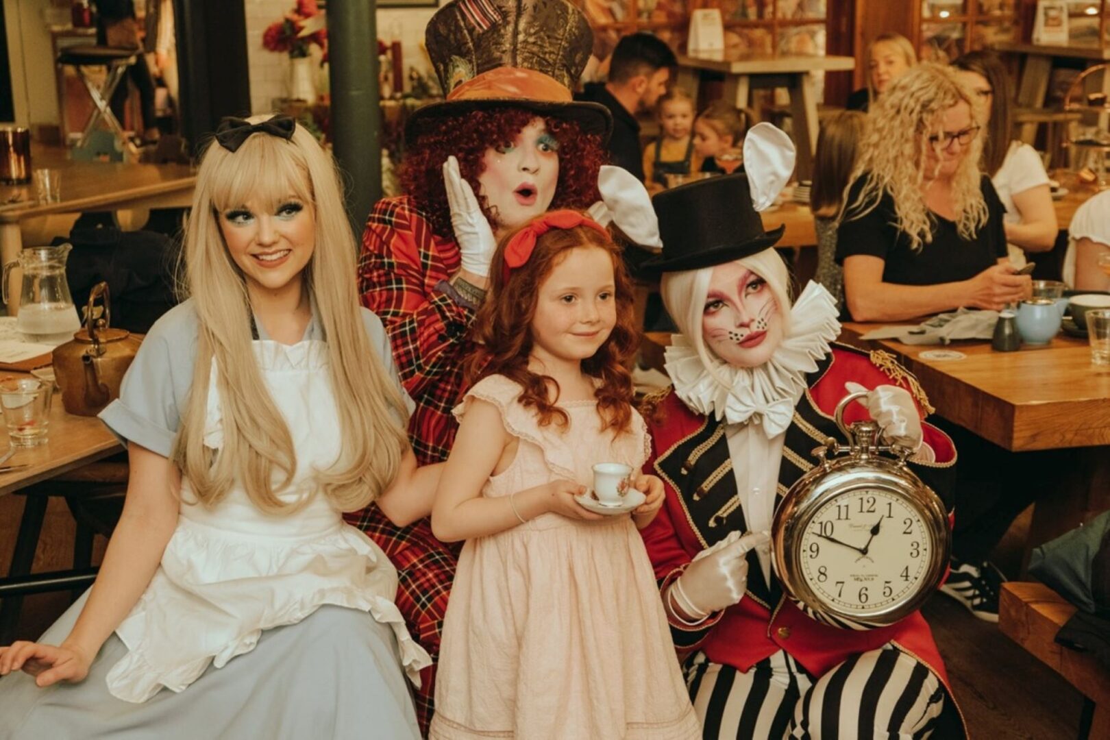 3 adults dressed in fancy dress, standing beside a young girl.