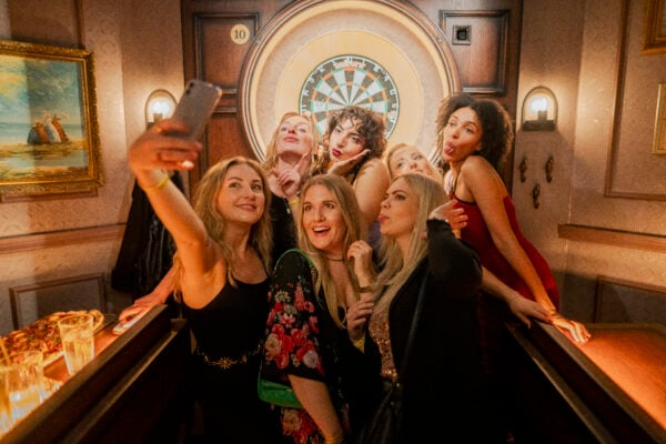 Graduates celebrating at Flight club with dart board behind