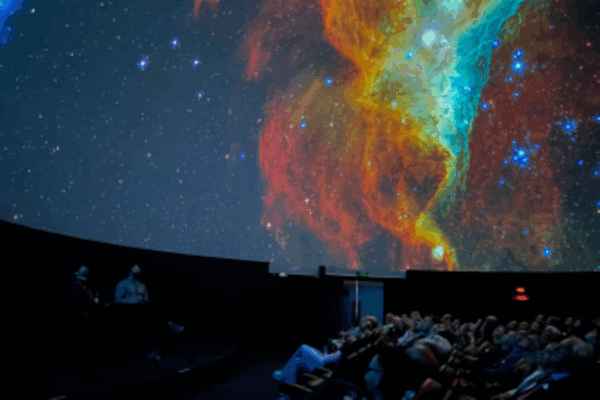 A theatre of people looking up at the earth's sky, in shades of red, yellow, blue and white.