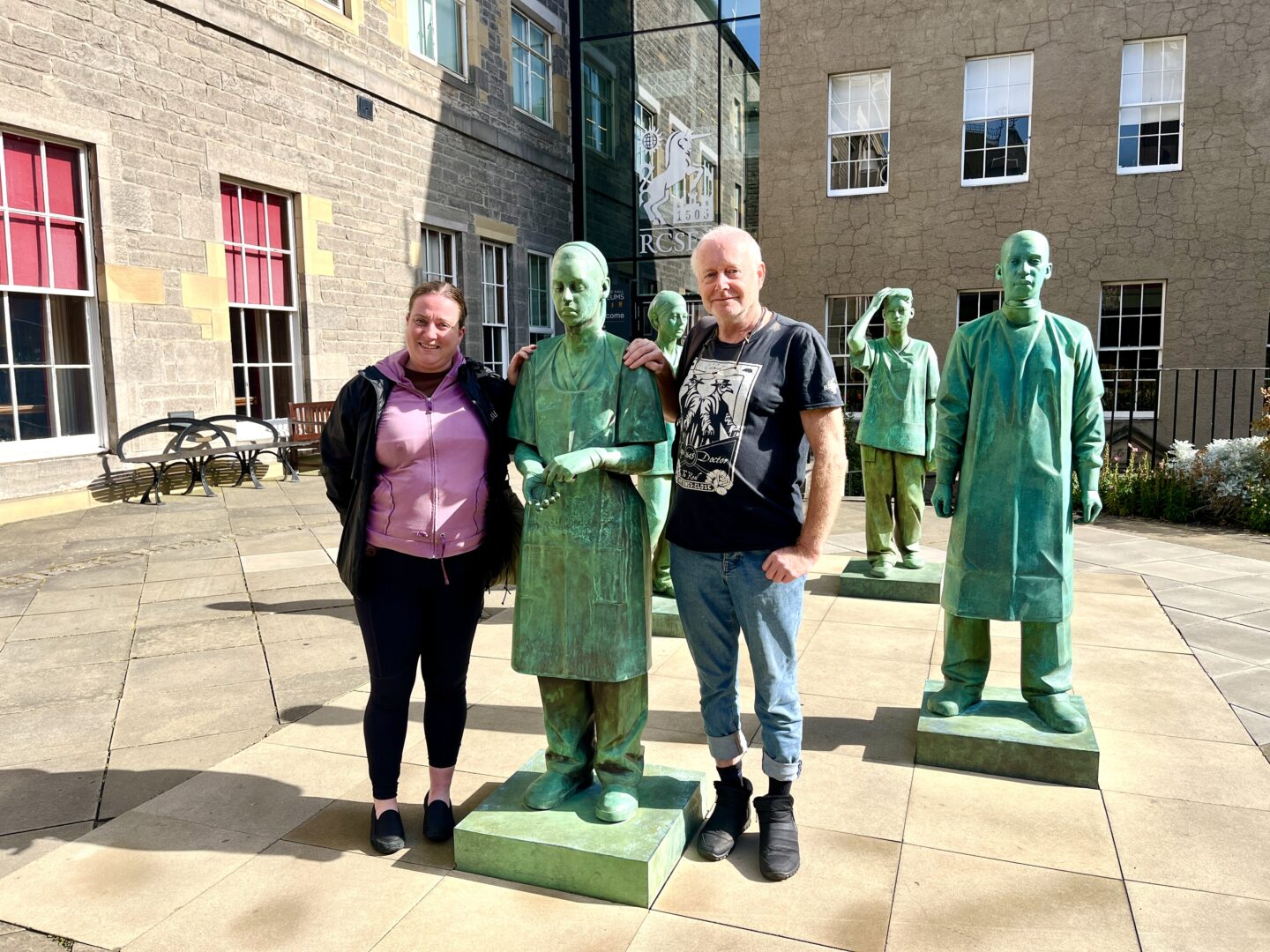 A woman and man standing with a statue of a famous inventor