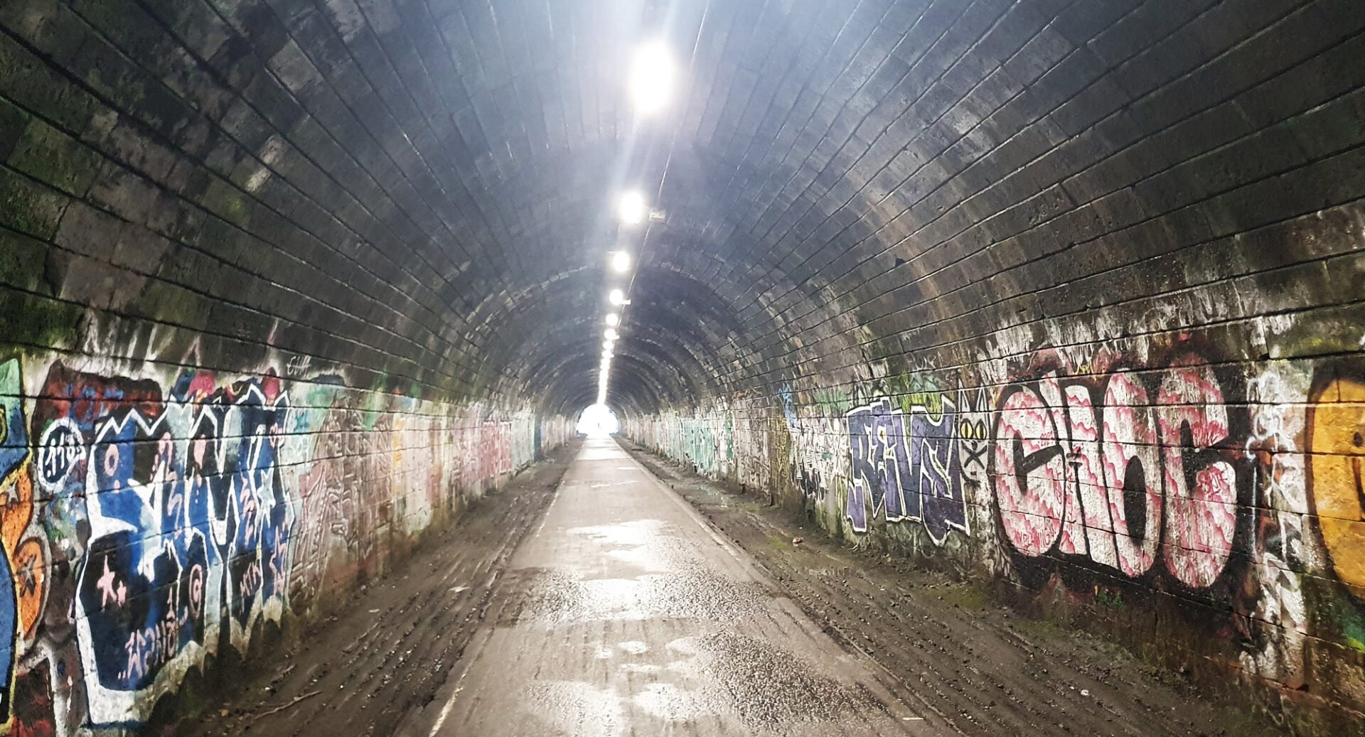 An underground tunnel, with graffiti on the walls.