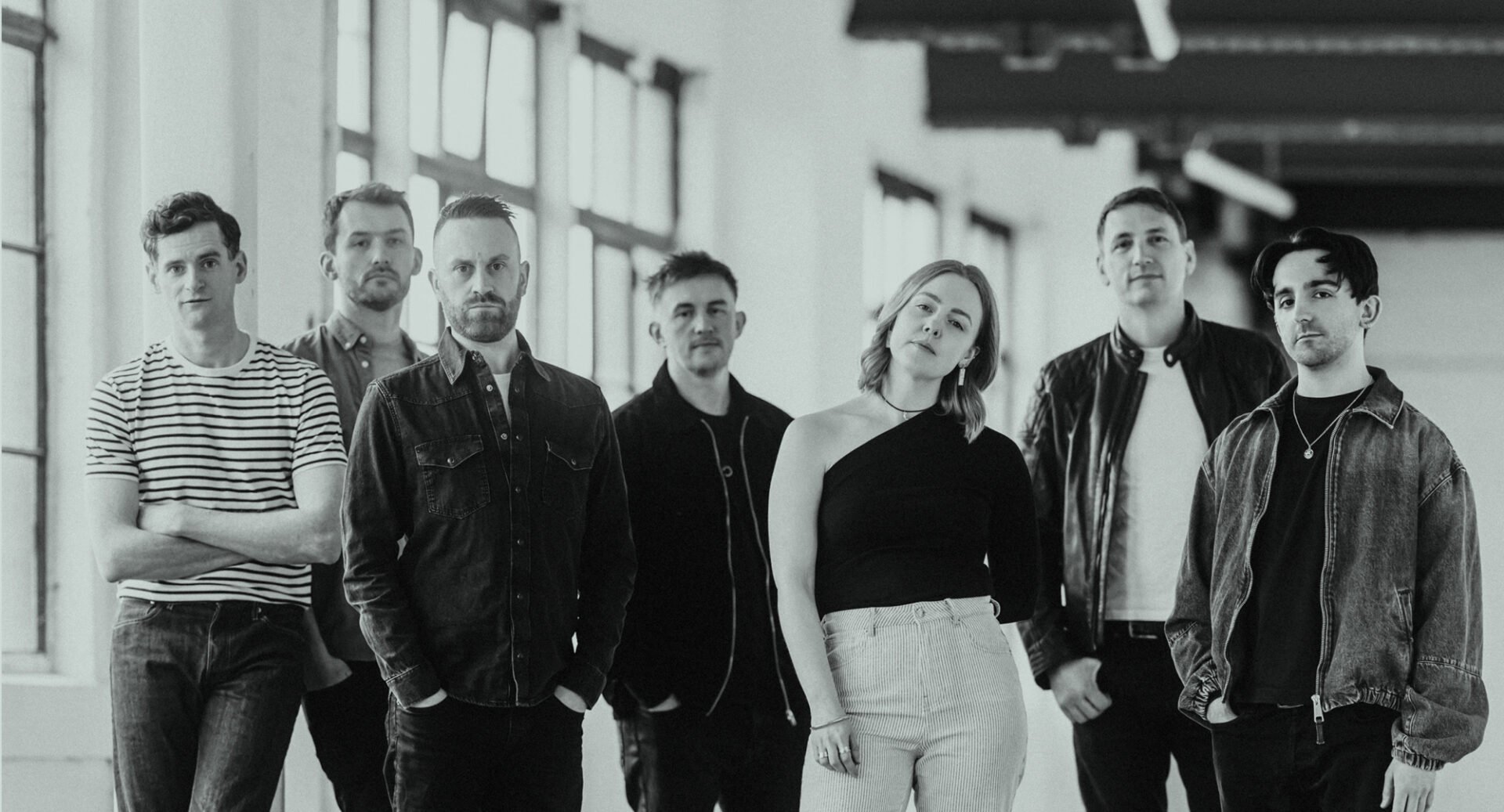 Black and white image of a group of people standing, looking straight ahead.