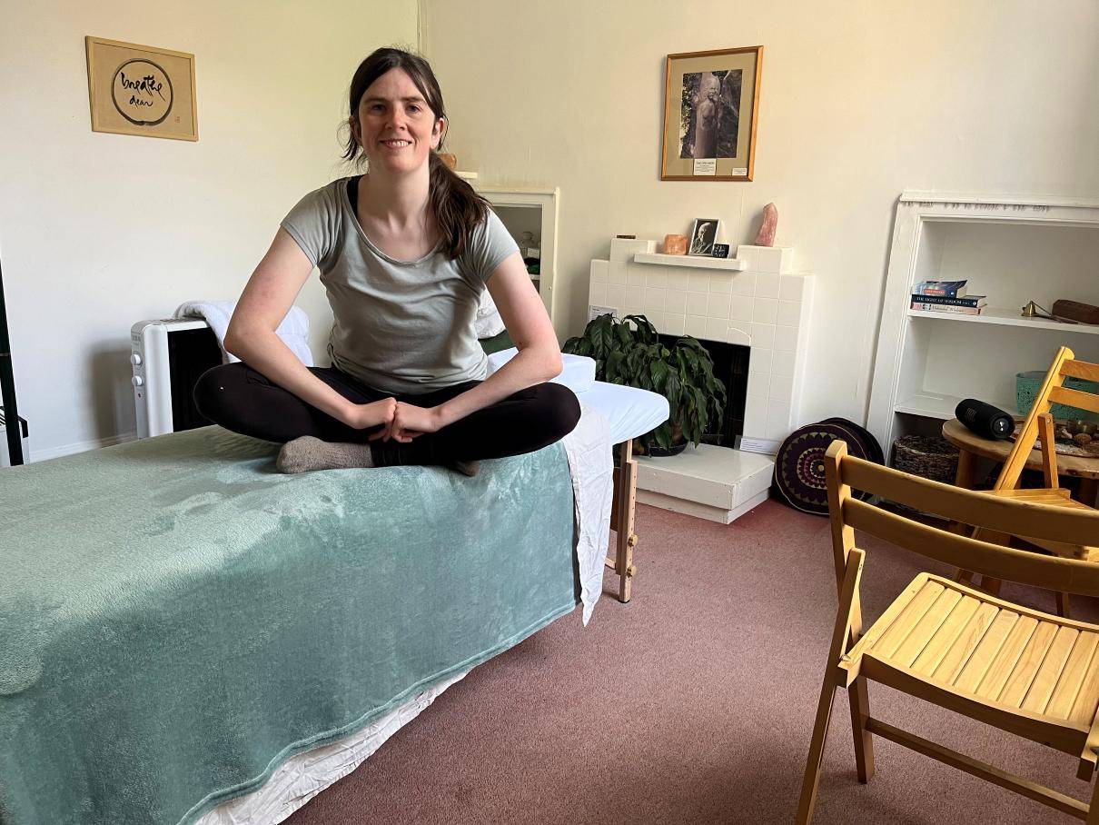 Jo who does Massage Therapy sitting on massage bed