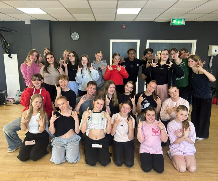 Group of children, some kneeling at front, and others standing behind, in a studio.