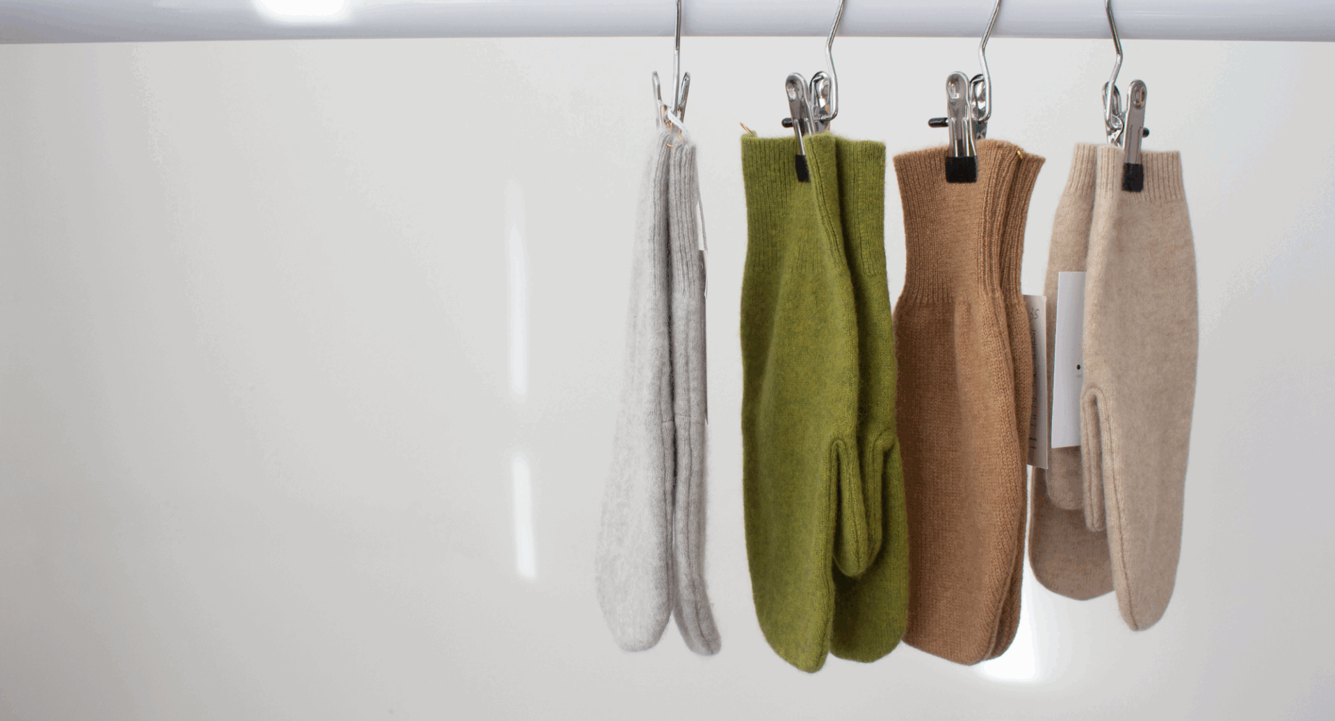4 pairs of mittens hanging on a pole.