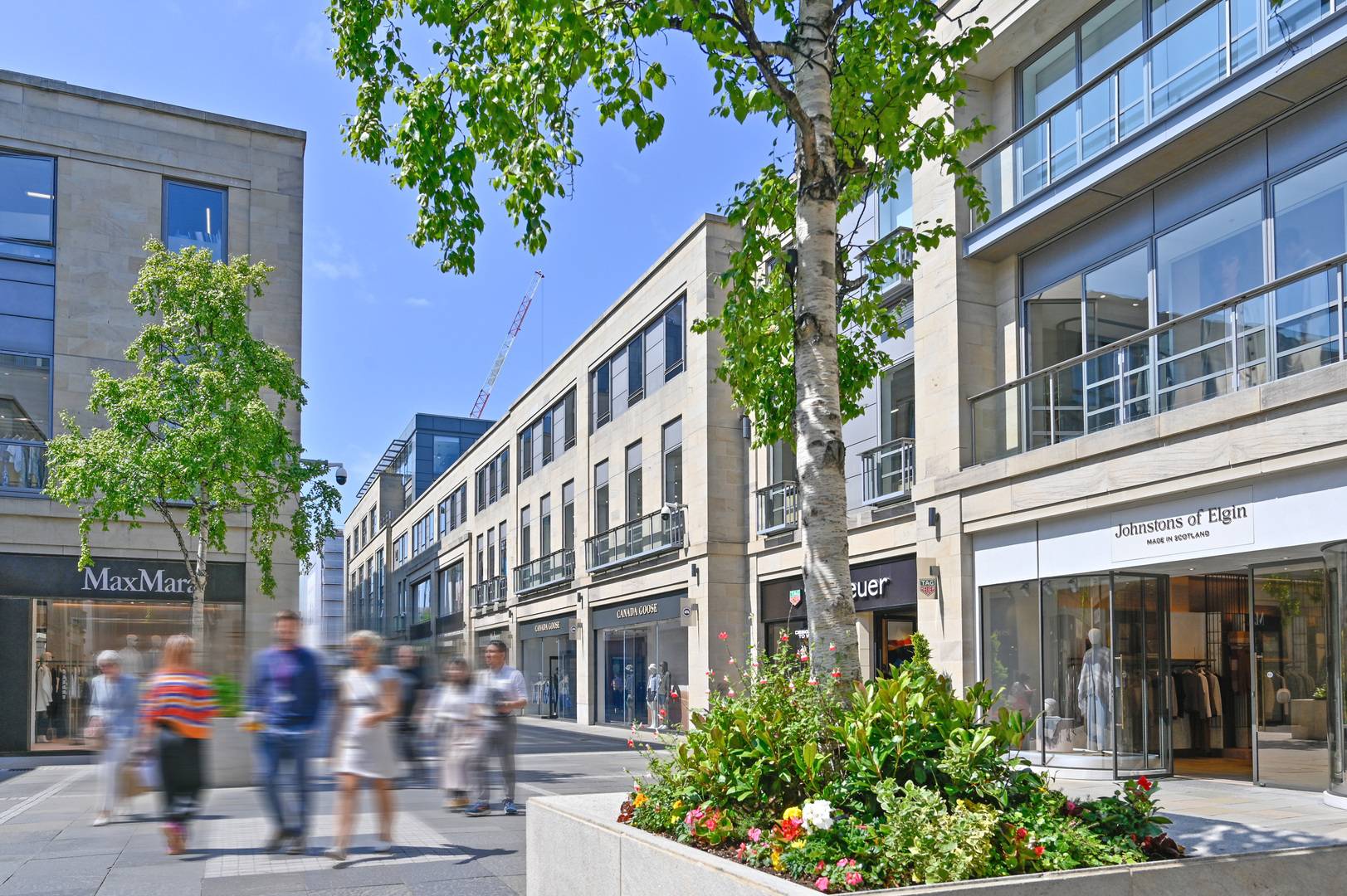 Main square at Multrees Walk with Johnstons of Elgin and Max Mara store frontages and two tree planters,© Multrees Walk