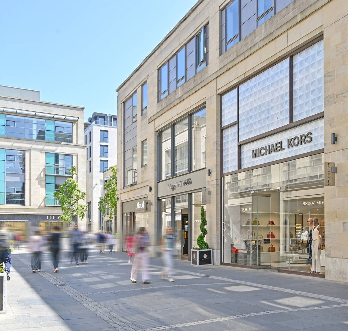 Multrees Walk walkway lined with brand store frontages including Michael Kors, Mappin & Webb and Max Mara,© Multrees Walk