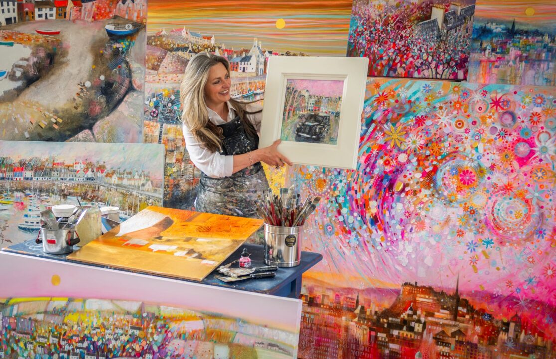 Women standing amongst a number of brightly coloured paintings.