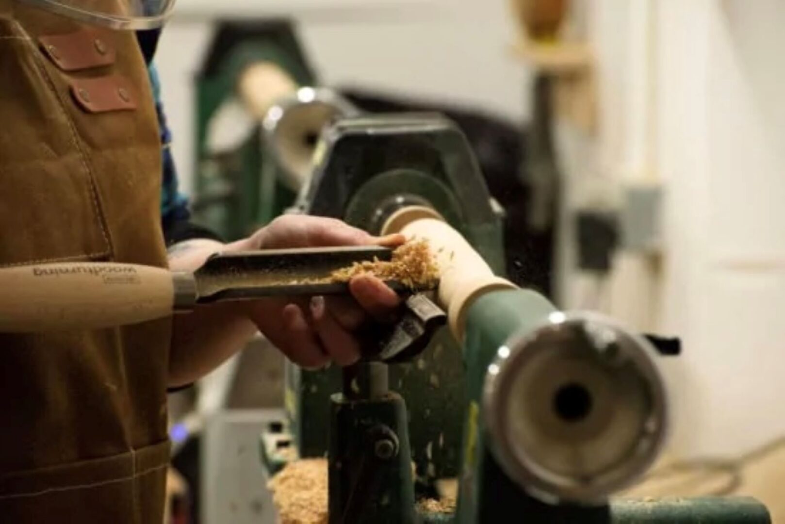Person using a machine to shape a piece of wood.