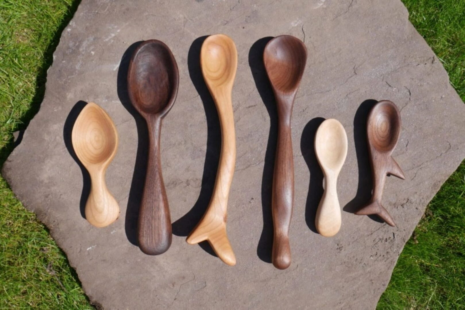 6 different sized wooden spoons laid on a large piece of slate.