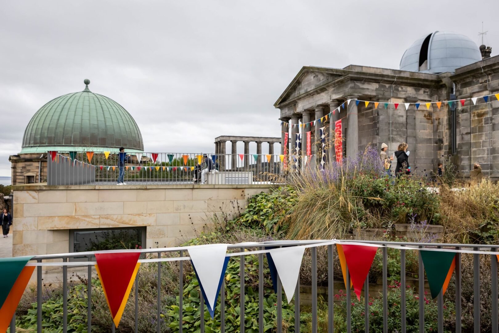2 large stone buildings, each with a dome on the top, decorated with coloured flag bunting.